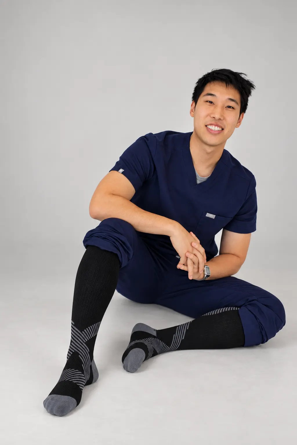 Nurse in navy scrubs sitting on the floor wearing NursingRx compression socks